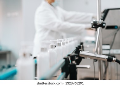 Picture Of Bottles With Hair Conditioner In Row On Exit Of Pouring Machine. Chemical Factory Interior. In Background Chemist.