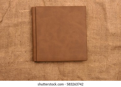 Picture of brown leather photo album cover on jute background. Keeping memories alive throughout the years