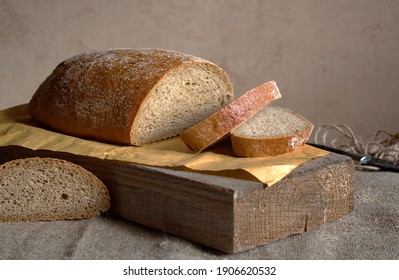 A picture in brown tones on a rough wooden board and textile cut fresh rustic bread - Shutterstock ID 1906620532