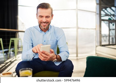 Picture of businessman typing on his smart phone at office lobby during coffee break - Powered by Shutterstock