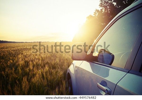 Picture of car in the field on background of magnificent\
sunset 