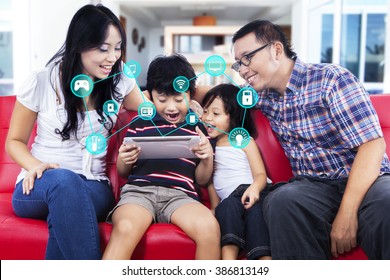 Picture Of Cheerful Asian Family Using Digital Tablet Computer With Smart Home Applications At Home