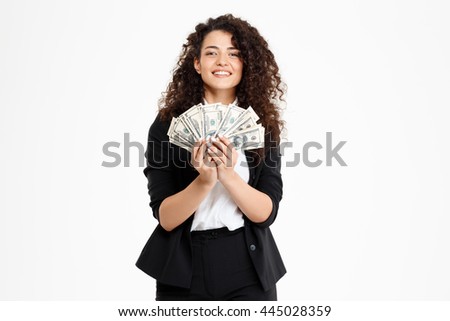 Picture of cheerful curly business girl holding money over white background