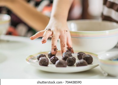 A picture of child's hand try to making chocolate cake pops recipe.