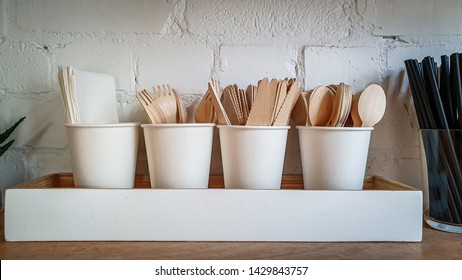 Picture of a coffee shop cutleries, spoons forks, knives, straws. White brick wall background, wooden plywood table, white laminated wood casing.  - Shutterstock ID 1429843757