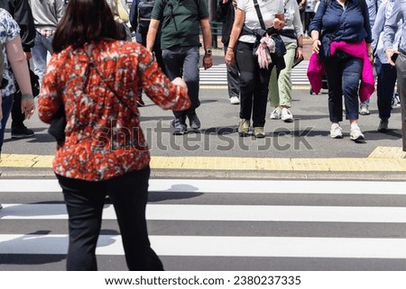 picture of crowds of people crossing a city street at the zebra crossing