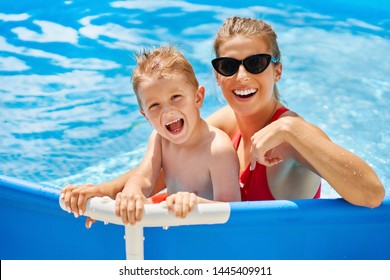 Picture of cute boy with his mother playing in a pool of water during the summer