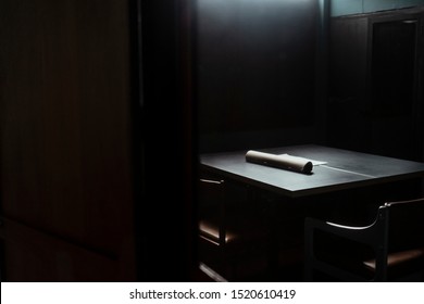 A Picture Of Dark Interrogation Room That Has A Bit Of Light Shining Up Side.