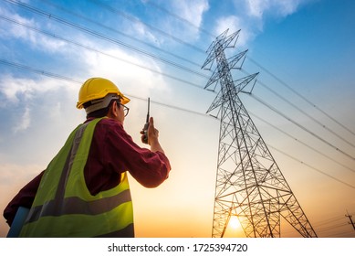 Picture of an electrical engineer standing and watching at the electric power station to view the planning work by producing electricity at high voltage electricity poles. - Shutterstock ID 1725394720