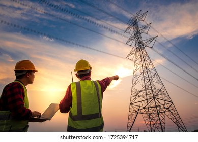Picture of an electrical engineer with two workers talking to each other working and checking work at a power station. Engineers look at the work and plan the high voltage poles. - Shutterstock ID 1725394717