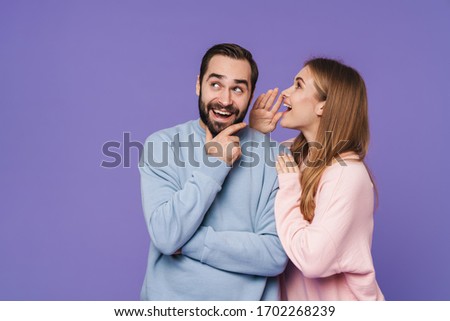 Picture of emotional positive young loving couple isolated over purple background gossiping talking with each other. Foto stock © 