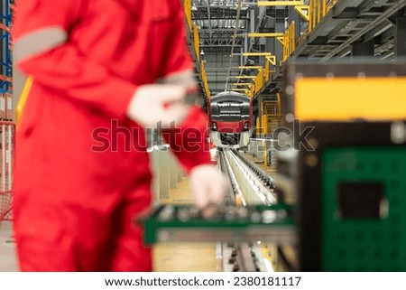 Picture of engineer using repair tools of the electric train industry There is an electric train in the train repair factory as the background image.