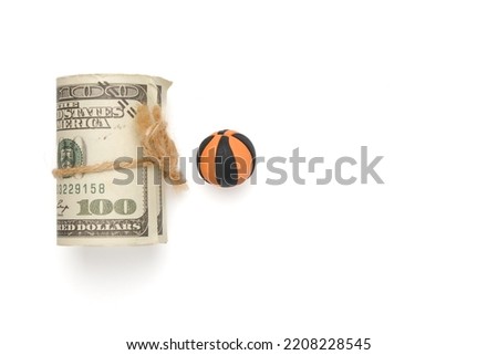 A picture of fake cash and basketball ball miniature on copyspace white background.