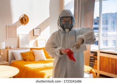 Picture Of An Female In White Chemical Suit And Gas Mask At Home In A Large Light Room Desinfects Herself