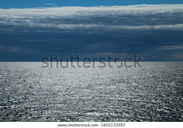 The Picture from a ferry between Sweden and\
Finland. The contrast between the dark cloudy sky and bright water\
with sun reflection.