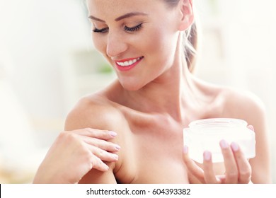 Picture of a fit woman holding lotion over her body
