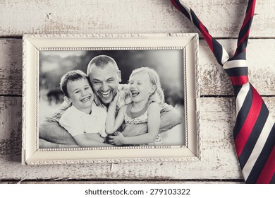 Picture Frame With Family Photo And Colorful Tie Laid On Wooden Backround.