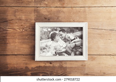 Picture Frame With Family Photo Laid On A Wooden Background.