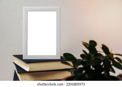 A Picture Frame Placed On A Book With A Small Plant Pot