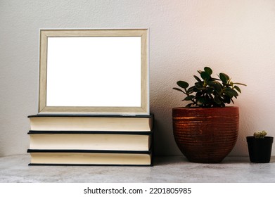 A Picture Frame Placed On A Book With A Small Plant Pot