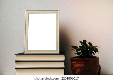 A Picture Frame Placed On A Book With A Small Plant Pot