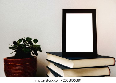 A Picture Frame Placed On A Book With A Small Plant Pot