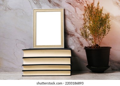 A Picture Frame Placed On A Book With A Small Plant Pot