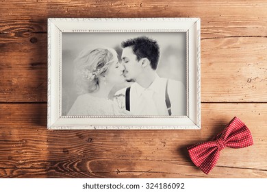 Picture Frame With Wedding Photo. Studio Shot On Wooden Background.