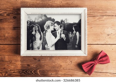 Picture Frame With Wedding Photo. Studio Shot On Wooden Background.