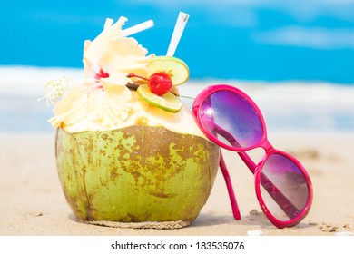 picture of fresh coconut cocktail and red sunglasses on tropical beach - Powered by Shutterstock