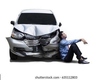 Picture of a frustrated businessman sitting next to a damaged car after accident, isolated on white background