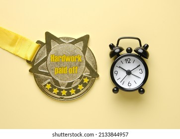 A Picture Of Gold Medal With Hardwork Paid Off Word, 6 Stars And Alarm Clock. Motivational Quote