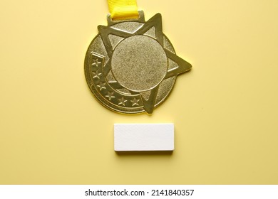 A Picture Of Gold Medal With White Wooden Block On Yellow Background. Getting Gold Medal Concept