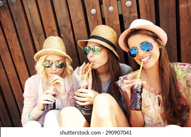 A Picture Of A Group Of Girl Friends Drinking Soda On The Pier