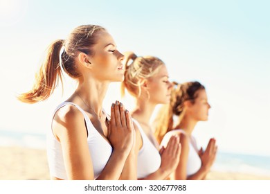 A Picture Of A Group Of Women Practising Yoga On The Beach