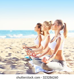 A Picture Of A Group Of Women Practising Yoga On The Beach