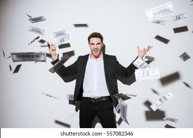 Picture of handsome businessman posing at studio and look at camera while throws away money. Isolated over white background.