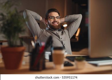 Picture Of Happy Bearded Designer Dressed In Shirt Working Late At Night With Computer And Stretching