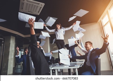 Picture Of Happy Business Team Celebrating Victory In Office. Woman Stand On Table