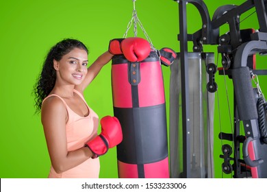 Picture of happy Indian woman leaning on a boxing bag in the studio with green screen background - Powered by Shutterstock