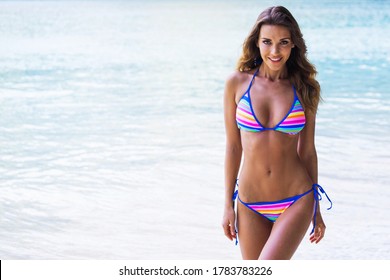 Picture of happy woman with perfect body in bikini on tropical beach, sea on background, copy space for text