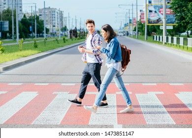 A picture of a happy young couple students on a walk on a day off. A happy friends crosses the road at a pedestrian crossing. Side view