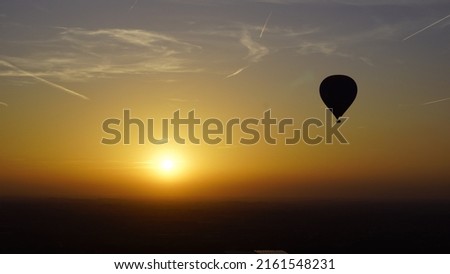 Picture of a hot air balloon whilst flying in the air. In the background the sun sets.