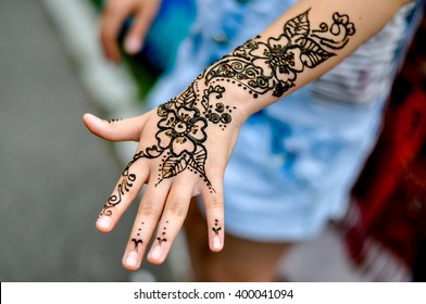 Picture of human hand being decorated with henna tattoo