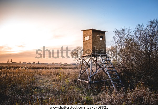 Picture of a hunting tower or a raised hide or\
blind on a field at\
dawn.