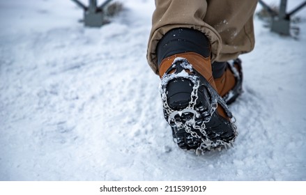 A picture of ice cleats being worn on boots by a person in the woods.