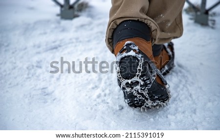 A picture of ice cleats being worn on boots by a person in the woods.
