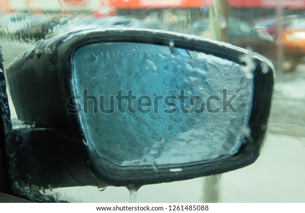 Picture of an iced\
car mirror and window. Photographed from inside the cabin through a\
frozen window. Blurred