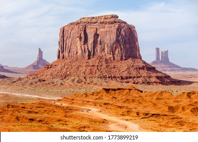 Picture Of Iconic Merrick Butte Rock Formation In Oljato-Monument Valley Taken On A Summer Cloudy Day From John Ford's Point. The Scenic Drive Dirt Road With Tourist Cars Winds Through The Red Sand.