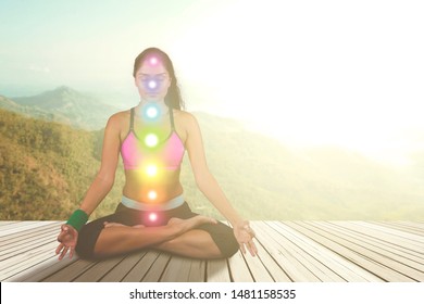 Picture of Indian woman doing meditation with colored chakra points on her body. Shot at nature